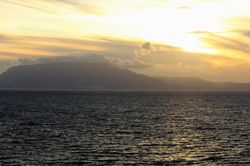 evocative image of sunset over the sea with headland silhouette in the background