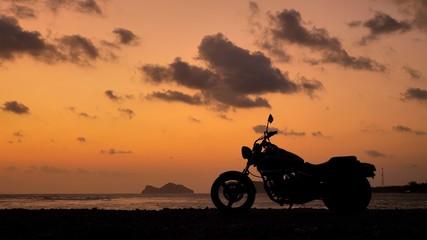 Fototapeta premium Motorcycle silhouette at sunset time near sea coast line