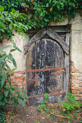 Old broken wooden door in brick wall. Entrance to the secret garden