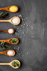 Colorful spa salt in spoons on grey background top-down frame copy space