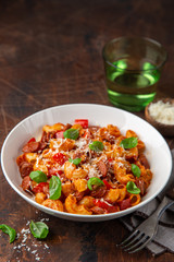 Spicy sausages marinara pasta with parmesan cheese and fresh basil in white bowl