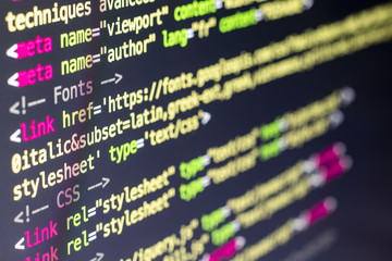  Close-up and focus on a part of the computer screen displaying the code of a web page in an html file - Modern technologies - HTML code of a website with colored tags - Small focus area