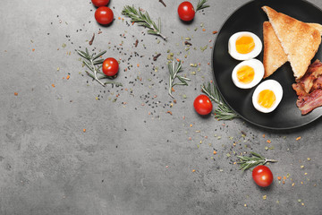 Plate with boiled eggs, bacon and toasted bread on dark background