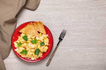 Plate with scrambled egg and toasted bread on table