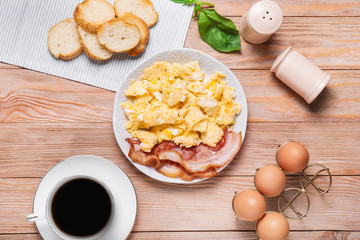 Plate with scrambled egg and bacon on table