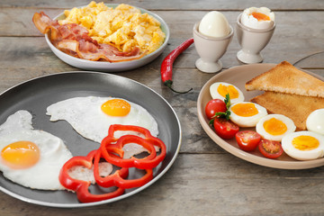 Different tasty dishes with eggs on wooden table