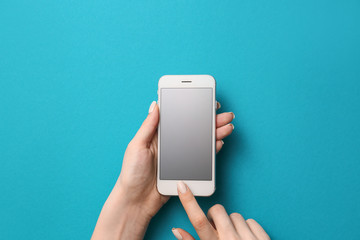 Female hands with mobile phone on color background