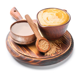 Jug of tasty honey mustard sauce with ingredients on white background