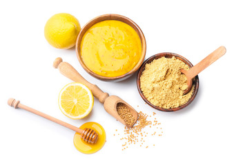 Bowl of tasty honey mustard sauce with ingredients on white background