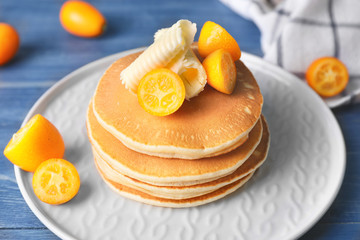 Tasty pancakes with butter and citrus fruit on plate