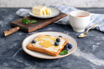 Tasty toasted bread with honey, butter and berries on table