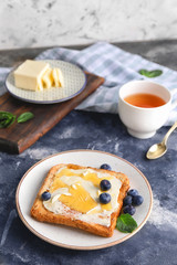 Tasty toasted bread with honey, butter and berries on table