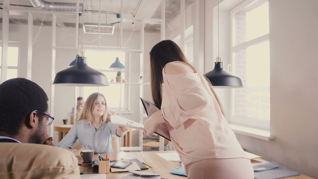 Camera Follows Woman Leader Motivating Workers. Female Boss Walks And Talks To Mixed Race Colleagues In Trendy Office 4K