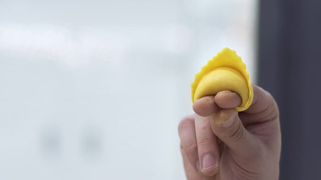 Handmade organic healthy Italian pasta called tortello or raviolo, traditional Italian stuffed pasta. Chef or cook folding the dough and shaping it.