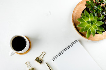 White fashion feminine home office workspace with succulent, cup of coffee, blank paper notebook, pen and clips. Top view. copy space, flat lay. Mockup concept