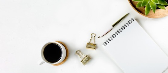 White fashion feminine home office workspace with succulent, cup of coffee, blank paper notebook, pen and clips. Top view. copy space, flat lay. Mockup concept. Banner image for website