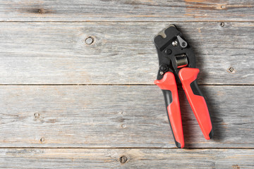 Tool for crimping stranded electrical wires. Crimping tool for electrician or Builder on a grey wooden background