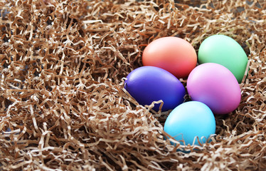 Easter pastel colored eggs lie on a decorative paper hay. selective focus. Easter still life
