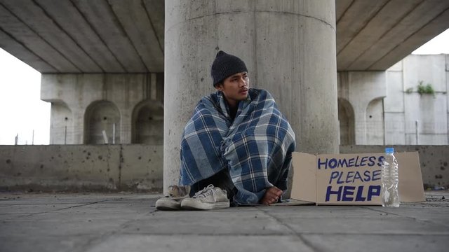 Dramatic portrait of a little homeless boy on the bridge, poverty, city, street