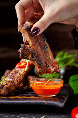 Mexican cuisine. Grilled pork ribs with hot pepper, white and red sauce. Serving dishes in a restaurant on a black plate. background image, copy space text