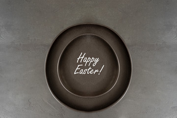 Black Egg Shaped Plate on dark large background. Minimalist style. Happy Easter concept. Copy space