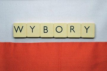ELECTIONS (polish: wybory) word made from  game tiles with letters.  Selective focus. Elections in Poland theme. Letters on the background with white and red flag of Poland - obrazy, fototapety, plakaty