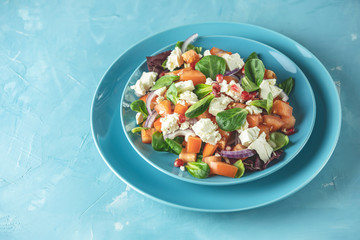 Blue plate of fresh superfoods healthy salad with red onion, tomatoes, doucette (lambs lettuce, corn salad, field salad) and feta cheese. Light blue surface