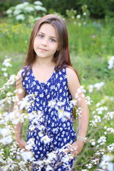 Fototapeta premium young beautiful girl in blue romper in floral print in the summer garden. Holidays and entertainment