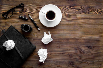 Journalist's desk. Notebook, pen, crumpled paper on dark wooden background top-down copy space