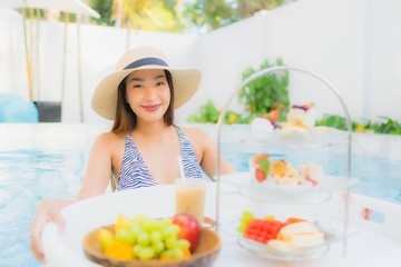 Portrait beautiful young asian woman enjoy with afternoon tea or breakfast floating on swimming pool