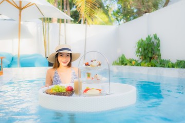 Fototapeta na wymiar Portrait beautiful young asian woman enjoy with afternoon tea or breakfast floating on swimming pool
