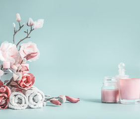 Beauty background with pastel pink flowers and cosmetic at pastel blue background