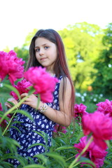 Naklejka premium Flowering peonies. Beautiful Caucasian girl with long brunette hair in a botanical garden where bright pink and white peonies bloom. Nature and relaxation. Botanical Garden. Flowers