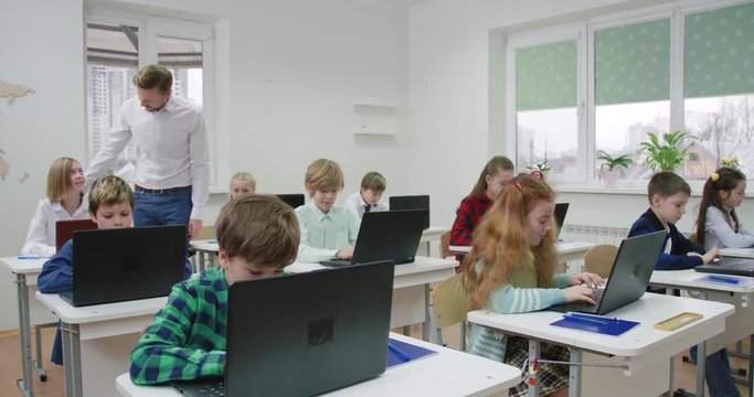 Education in the modern school, children use laptops, teacher monitors the implementation of the test work, the learning process at school.
