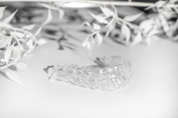 Invisible aligners teeth brackets on monochrome background with flower shadow