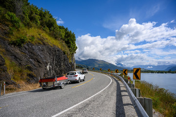 A white car with a boat Running on a curved road up the hill in the summer in wanaka lake, Tourists enjoy driving holiday trips on the South Island of New Zealand.