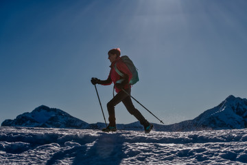 Sporty woman walks on snow with crampons and sticks