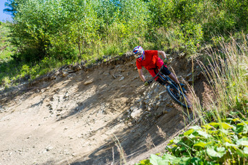 A rider on a mountain bike and in full-face helmet rides on stones.