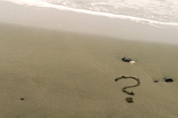 Question mark on sandy beach
