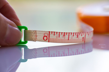 Woman's left hand hold Measure Tape ruler metric measurement, Metric ruler, White acrylic background, Close up and macro shot, Selective focus, Creative idea concept