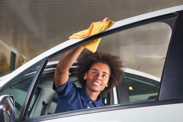 Polishing African woman as an apprentice at the car