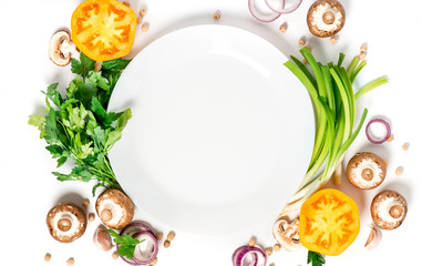 Fresh vegetables, chickpeas and herbs around blank white ceramic plate on a white background, top view, flat lay. Vegetarian or diet food concept. Food background.