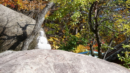 Small white statue of the Buddha in the autumn forest in Seoraksan national park, mount Sorak, Sokcho, South Korea.