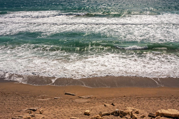 The foaming waves of the rough sea break on the beach.