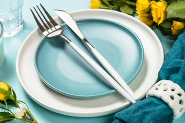 Spring table setting with flower on blue.