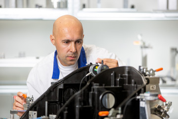 Quality engineer measuring plastic components by digital meter on the fixture, automotive and metrology concept