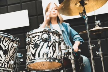 Fototapeta premium Creativity and music. Young beautiful girl plays the drums. Recording Studio. Musical equipment.