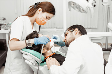 Obraz na płótnie Canvas Two dentists treat a patient. Professional uniform and equipment of a dentist. Healthcare Equipping a doctor’s workplace. Dentistry