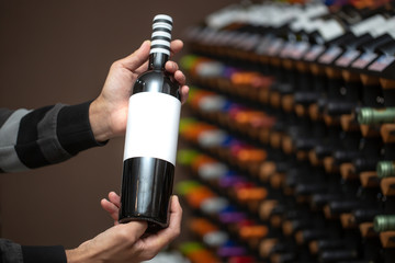 Close up of man hands holding very rare, red cork wine in the huge wine bar, wine degustation,...
