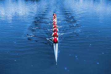 Boat coxed eight Rowers rowing on the blue lake. Classic Blue Pantone 2020 year color. - obrazy, fototapety, plakaty